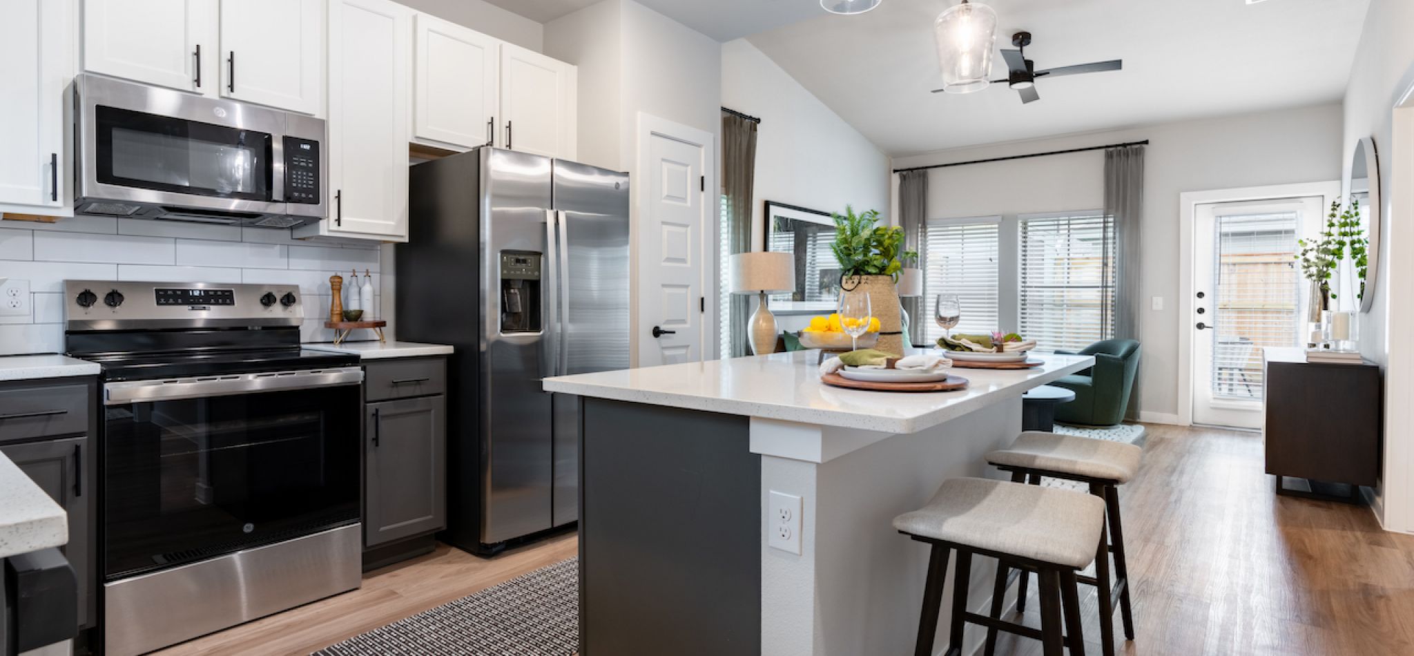 Artesia at Medina Valley apartment kitchen interior with kitchen island, stainless steel appliances, and white cabinetry